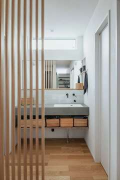 玄関ホールとの間に格子を設けてさりげなくゾーン分けした洗面スペース。デザインや仕様には奥さまのこだわりが反映されている