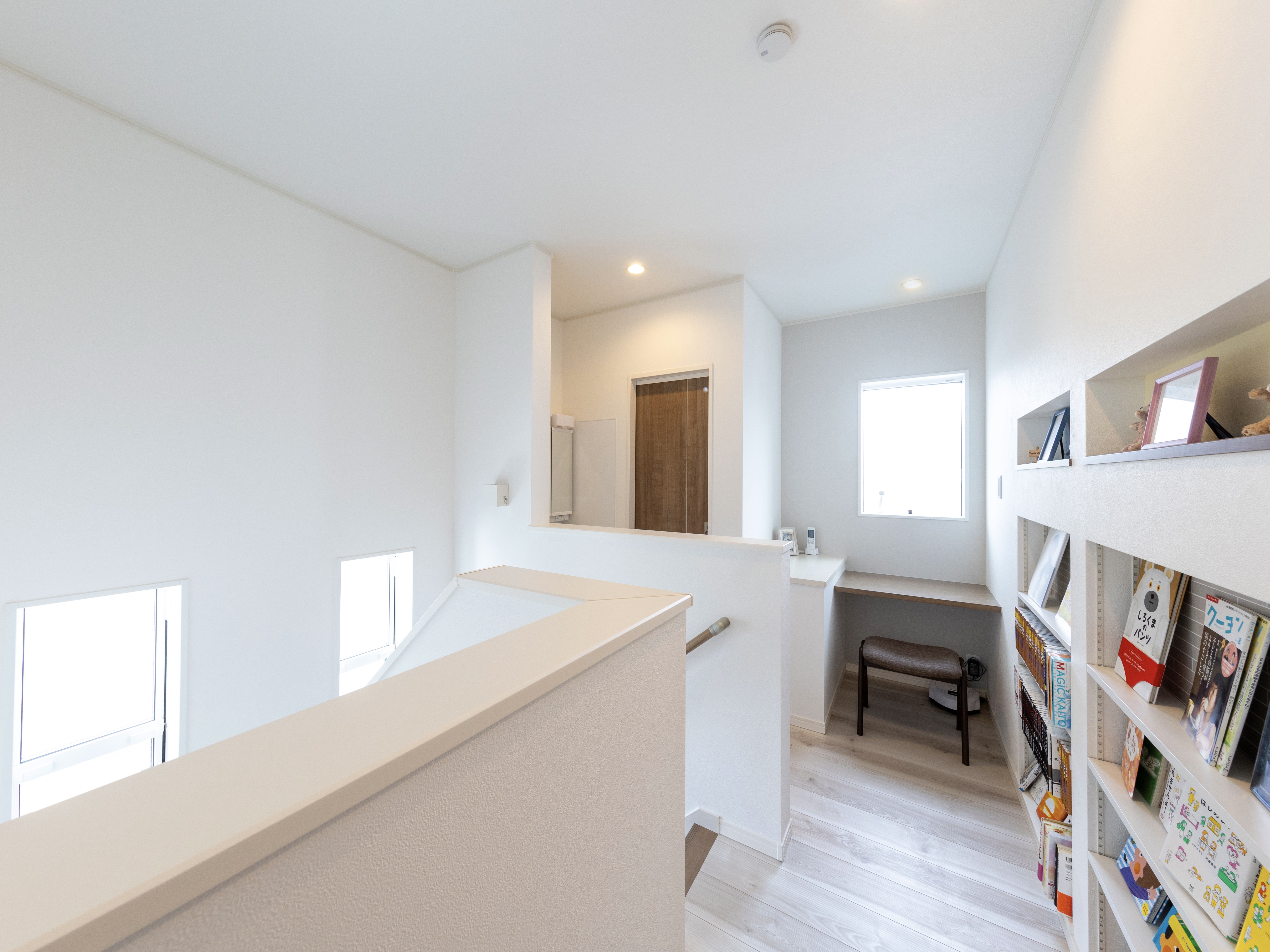 エスホーム｜明るい２階ホールには、ニッチの本棚と読書用のカウンターを設けた。ベランダ代わりの非常時脱出様にしたカウンター前の窓は、朝には明るい日差しが降り注ぐ。