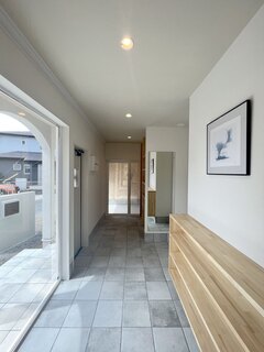 明るく開放的な玄関ホール。窓からの自然光が心地よく、ナチュラルな木製のシューズキャビネットが空間を引き締めている。