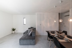 モノトーンで統一されたLDKの空間。シンプルでありながら洗練されたデザインが特徴。ダイニングとリビングスペースが一体となり、広々とした印象を与える。