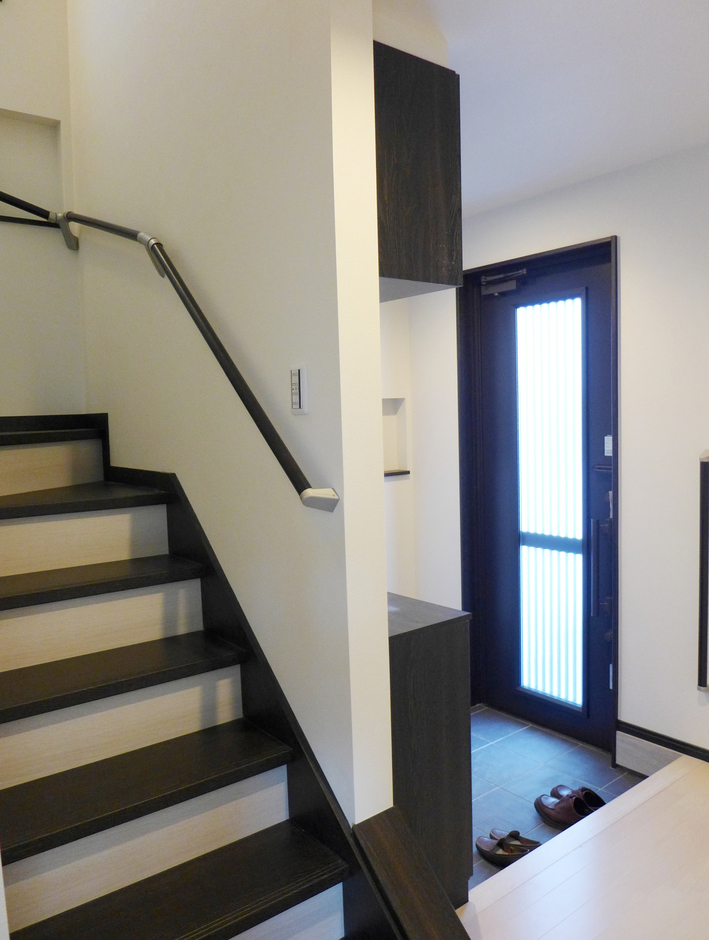 住宅の玄関ホールと階段はホワイトとダーク色のモノトーンな落ち着い 　　　　　　　　た雰囲気
