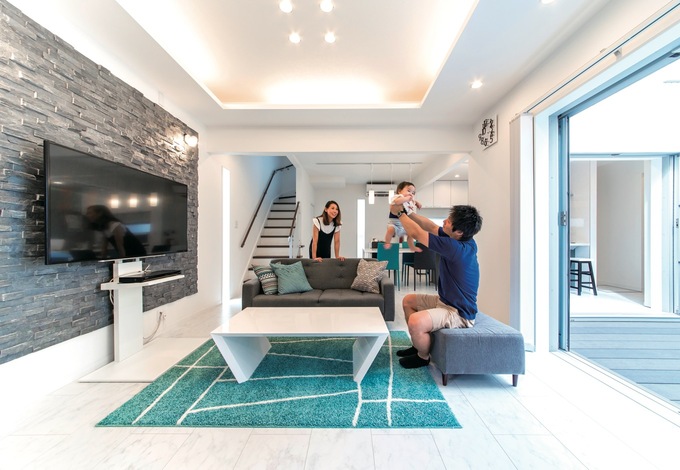 リビング、ダイニング、キッチン、中庭デッキを田の字型に配置。完全にプライバシーが守られる空間は、家族のくつろぎの場。折り上げ天井やテレビボードの背面にあしらった石材がアクセント