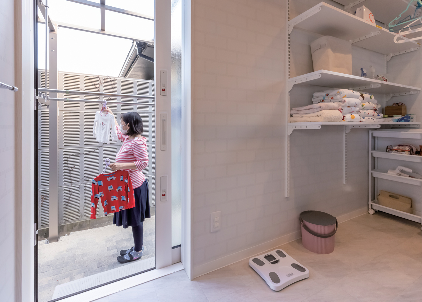 未来創建【子育て、省エネ、間取り】キッチンから短い距離でアクセスできるランドリールーム。収納棚と部屋干し用のポールを設置。外に干したいときは、勝手口から屋根付きのデッキへ