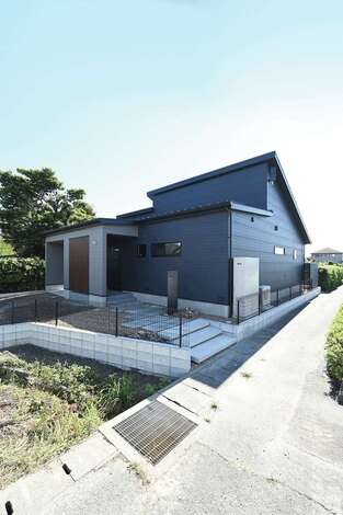 ガレージと小屋裏付きの外観は、一見2階建てのようにワイドな存在感。玄関ポーチに設けた格子がアクセントとなって外観を引き立てている。屋根の勾配面に太陽光発電のパネルを搭載