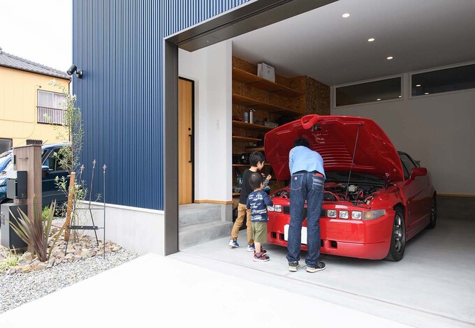 ご主人の愛車用のビルトインガレージには、車いじりができるスペースと収納棚を用意。玄関ポーチに繋がる出入り口もあり、雨天のときでも濡れずに行き来できる