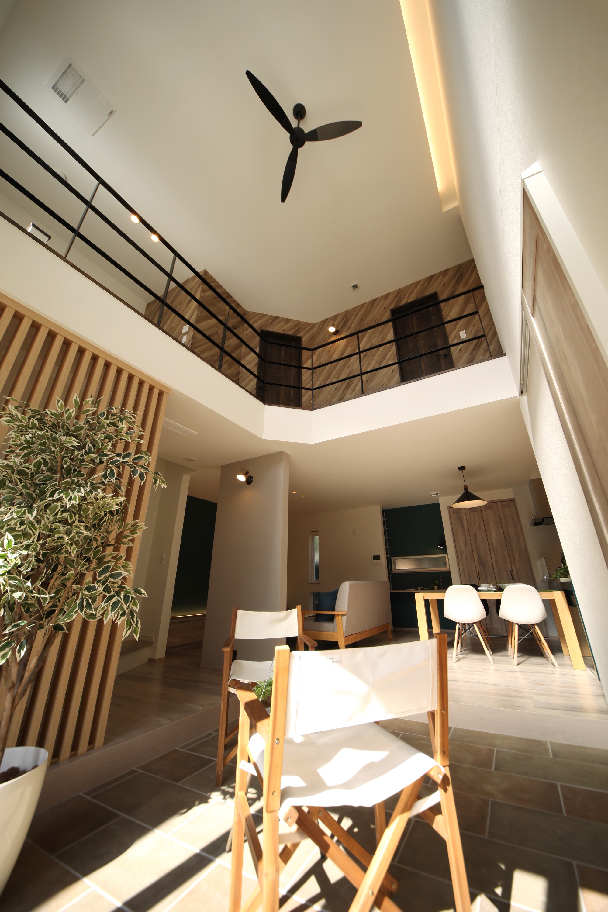 ホームラボ｜明るい自然光が差し込む開放的なLDK。吹き抜けの空間が広がり、天井ファンがアクセントとなっている。リビングとダイニングが一体となったデザイン。