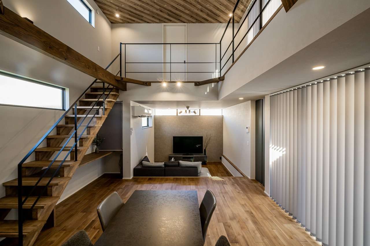 アーキテックス【デザイン住宅、趣味、間取り】開放感あふれる吹抜けのLDKは21畳。ヴィンテージ感と木のぬくもりに満ちた空間をアイアンが引き締めている。ロールスクリーンを開けると緑の中庭が広がる