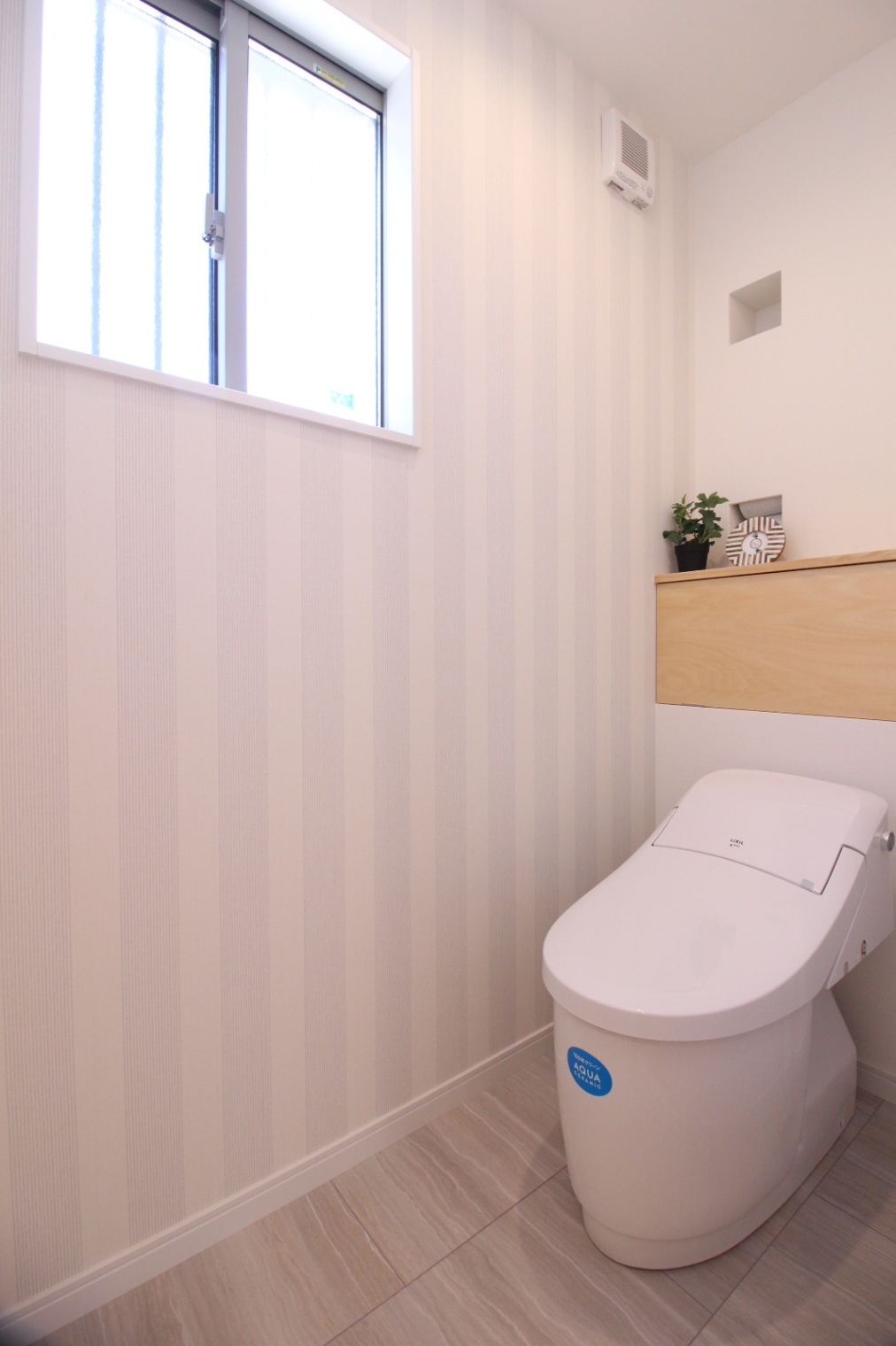 小野田産業～designers house project～｜壁紙のストライプが爽やかな印象のトイレ。シンプルながらも上品さを感じさせるデザインで、落ち着いた空間を提供する。