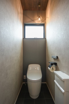 シンプルで落ち着いたトーンのトイレスペース。シーリングライトが柔らかな光を届け、リラックスできる空間を演出。