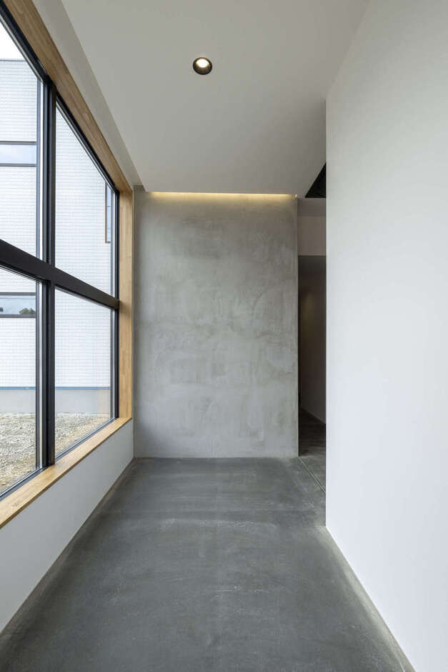 美容室の店舗の入り口。素材感を際立たせるために、飾りのないミニマルな空間をデザイン。モルタルの床と黒い金属の冷たく硬い表情が、モードな世界観を象徴する