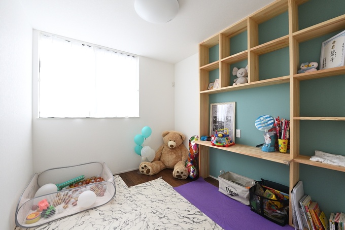 明るく楽しい雰囲気の子ども部屋である。おもちゃや絵本が整理されたオープン棚が特徴的で、小さなお子さんが自由に遊べるスペースが設けられている。
