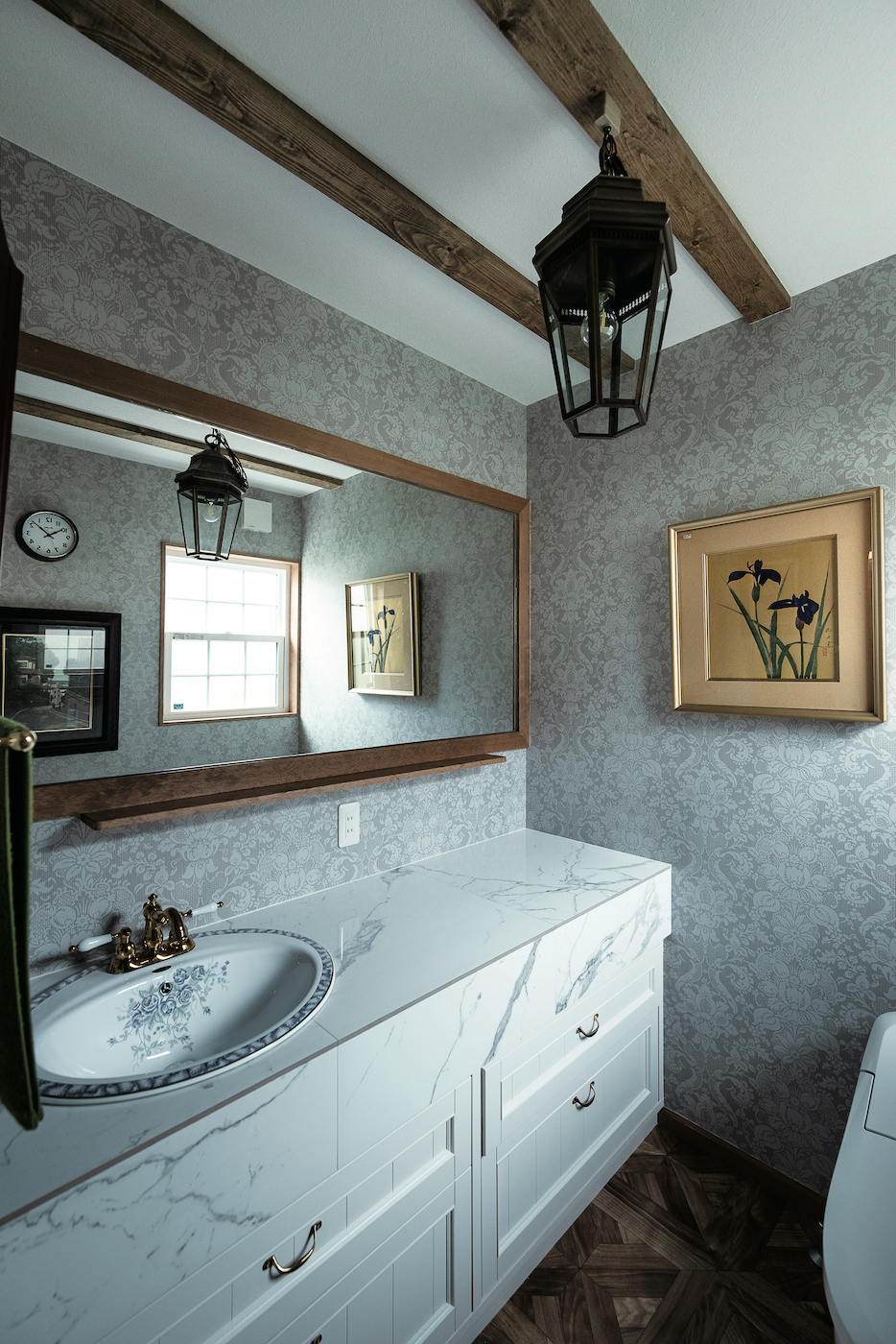 富士ホームズデザイン【デザイン住宅、自然素材、高級住宅】トイレの個室内に大きな鏡を備えた手洗い器を設置。白を基調にアクセントのゴールドを加え、エレガントで洗練された雰囲気に