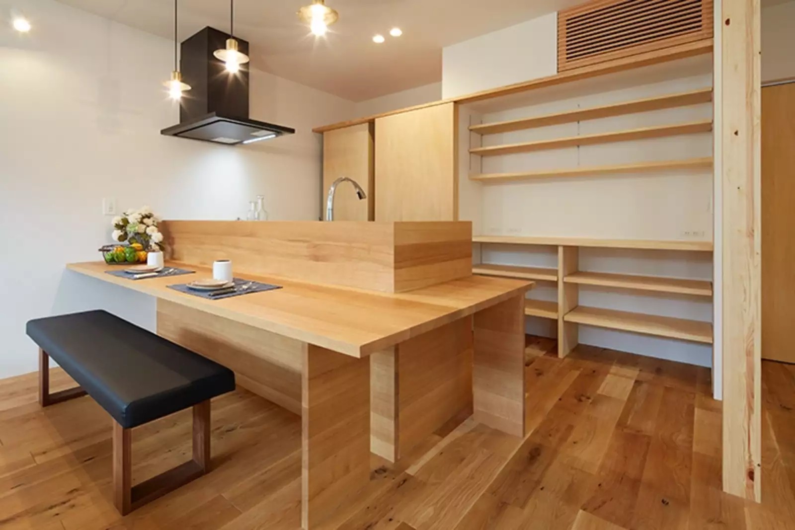 プライムライフ｜ナチュラルな木材を多用した造作ダイニング。
キッチン背面の収納は、扉ですべて隠せるようになっていて、実用性とデザイン性を兼ね備えている。