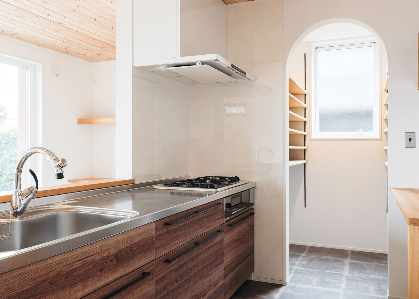 彩羽工藝舎【デザイン住宅、間取り、平屋】造作で収納棚を設けたキッチン。コンロはご主人こだわりの「ハーマン」製に。パントリー入り口はアーチ型にくりぬいた