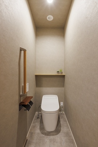 トイレはグレーを基調に、落ち着いた雰囲気にまとめている。
奥には造作棚を設け、ペーパー類やサニタリー用品をすっきり収納できる。