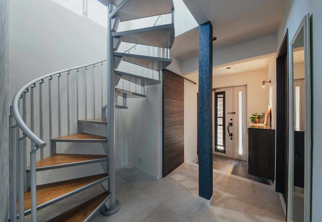 ハート住いる｜住まいの「顔」である玄関ホールに、アルミ製のらせん階段を設置。インテリアの一部として抜群の存在感を発揮する。既存の北側の窓から安定した光が届き、明るく開放的な空間に生まれ変わった