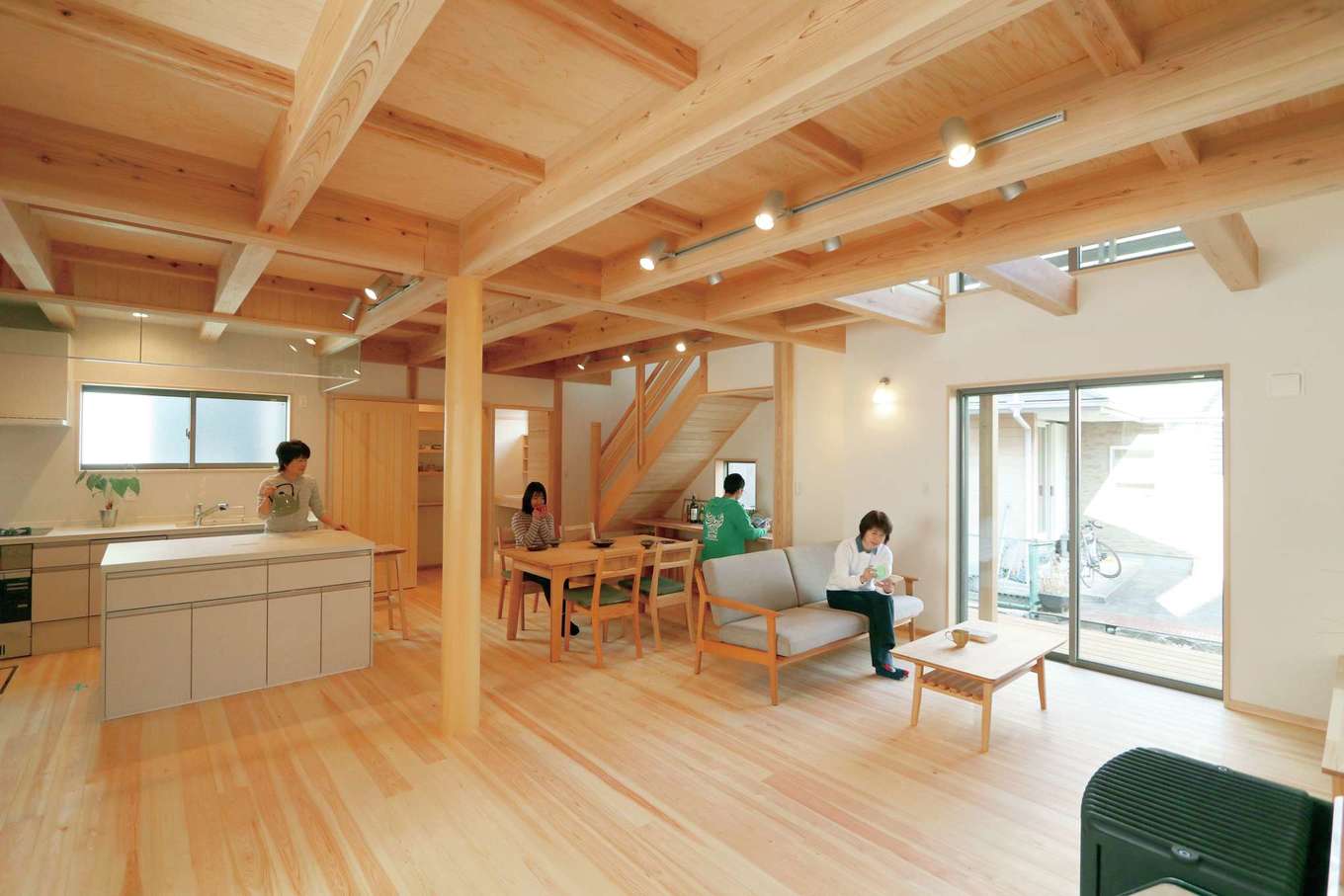 アクトホーム【自然素材、省エネ、間取り】開放感と安心感に満たされる空間に、パーティ、お菓子教室などを想定したオープンなキッチンや多目的に使える小上がりの畳スペースが有機的に連続する。階段下には造作カウンターを設け、空間を無駄なく活用。テーブルも大工の手によるものなので、雰囲気になじむのは当然。ペレットストーブのぬくもりは吹き抜けを通して2階にも運ばれていく