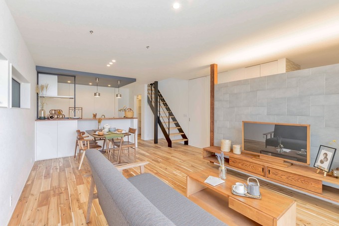 プライベートな時間を気兼ねなく楽しめるLDK。インテリアのアクセントにもなるスケルトン階段を境に、LDKと水回りを仕切り、プライベートスペースと生活スペースに程良い距離感を持たせた。キッチンの背面の収納は大きな扉で中を隠してお部屋のキレイをキープ。テレビ後ろの壁の向こうに配置した玄関とは、天井をつなげつつ、LDKは直接見えないように配慮した