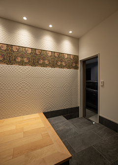 エコカラットとウイリアムモリスのアクセントクロスがクラシカルで上質な空間を演出する玄関ホール。雨に濡れずにガレージへアクセスできる動線は生活のしやすさにつながる