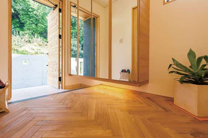 玄関のフロアはヘリンボーン模様に。収納面をすべて鏡にして広くみせる工夫も