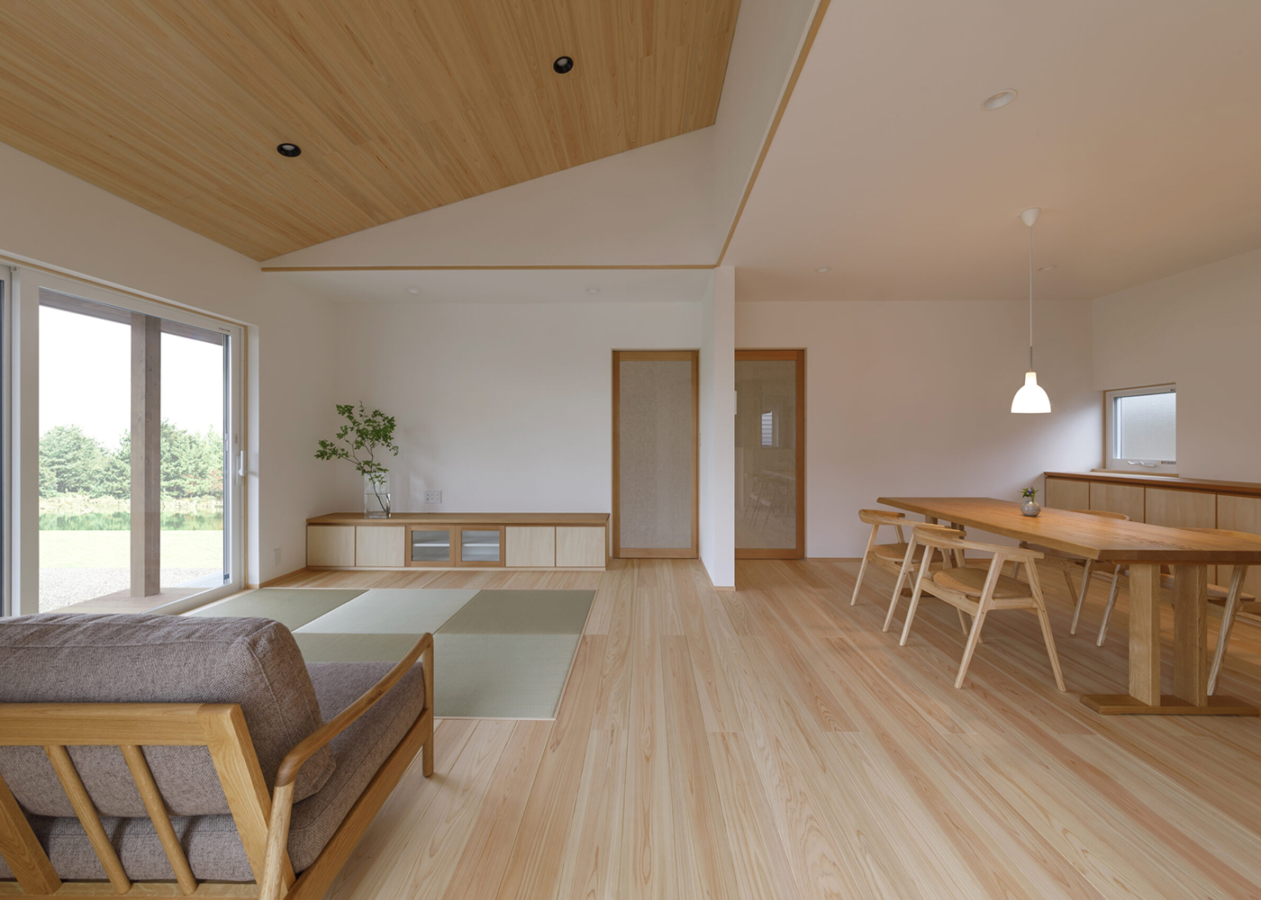 灯建築舎【デザイン住宅、和風、自然素材】勾配天井にもヒノキが張られ、大らかさで清々しい空間が完成。調和するように設けられた畳スペースが、和の落ち着きを添えている。テレビボードも造作。同社でよく採用される框戸は、二重のガラスの間に織布がはさまれたもので、光と気配を穏やかに透過させる