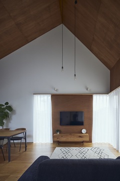 オーク材の床にラワン材の天井、三角屋根の形状を活かした吹き抜けのリビング