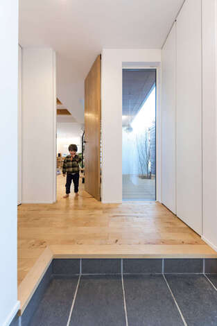 収納もドアも天井の高さに揃った玄関はスッキリとした空間。帰宅時は窓に映るインナーコートが気分をやわらげてくれる