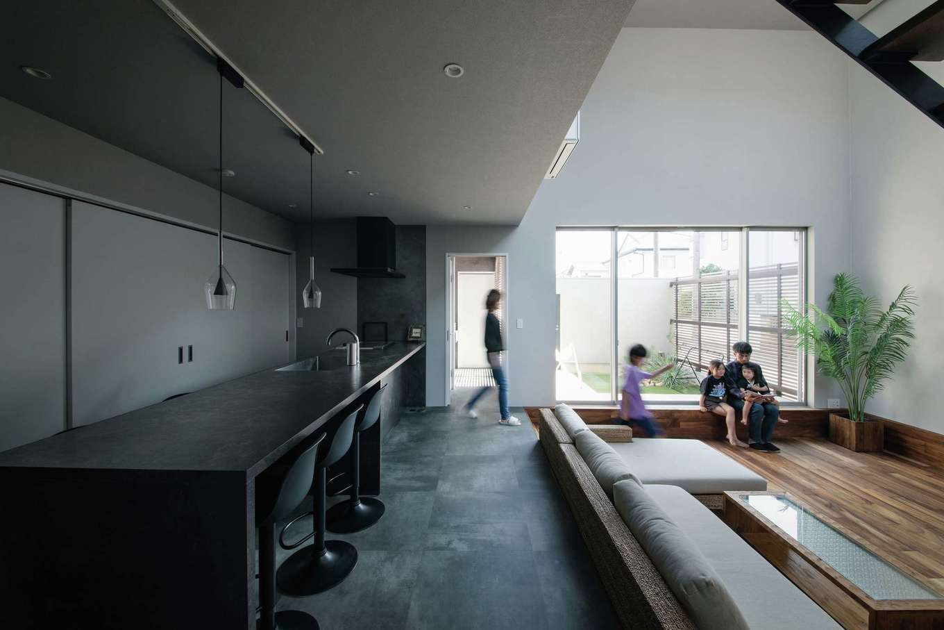 MABUCHI【デザイン住宅、子育て、建築家】ダウンリビングの床に無垢のアルビジアを使用し、観葉植物やメッシュ地のソファなど、アジアンリゾートの雰囲気を満喫できるLDKに。中庭から入る光と風が心地よく、非日常のホテルライクな暮らしを家族で楽しんでいる