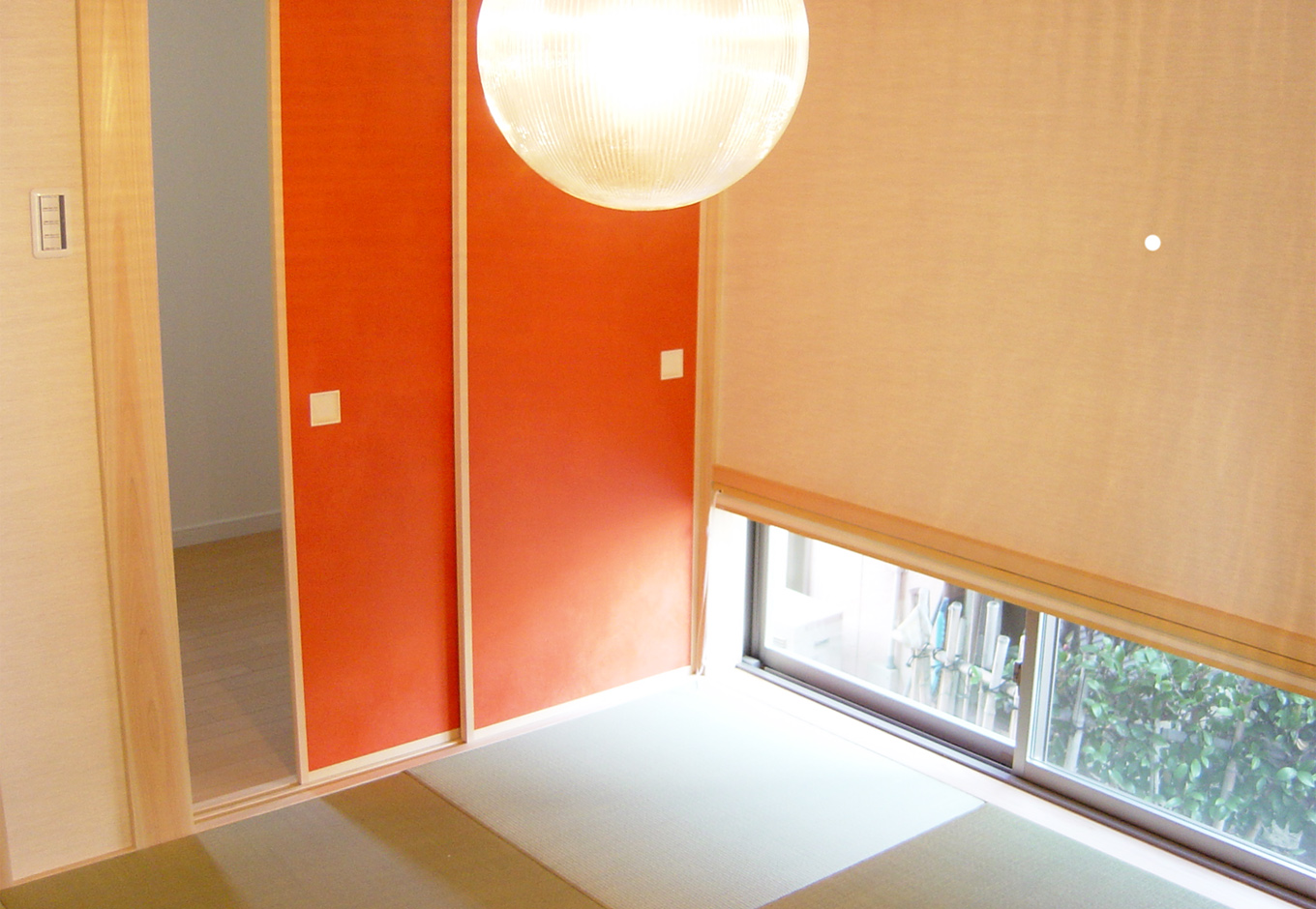 丸昇彦坂建設【デザイン住宅、収納力、和風】小上がりの畳スペースが広がる和室も、小窓を設けて庭を感じる造りに。温かみある照明の光がよく映える。オレンジ色の襖の向こうには、収納力抜群の納戸を用意
