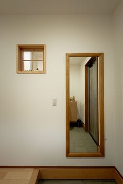 玄関に設置されたミラーと小窓。
光を取り込みつつ、奥行きを感じさせる工夫がなされている。シンプルで機能的なデザイン。