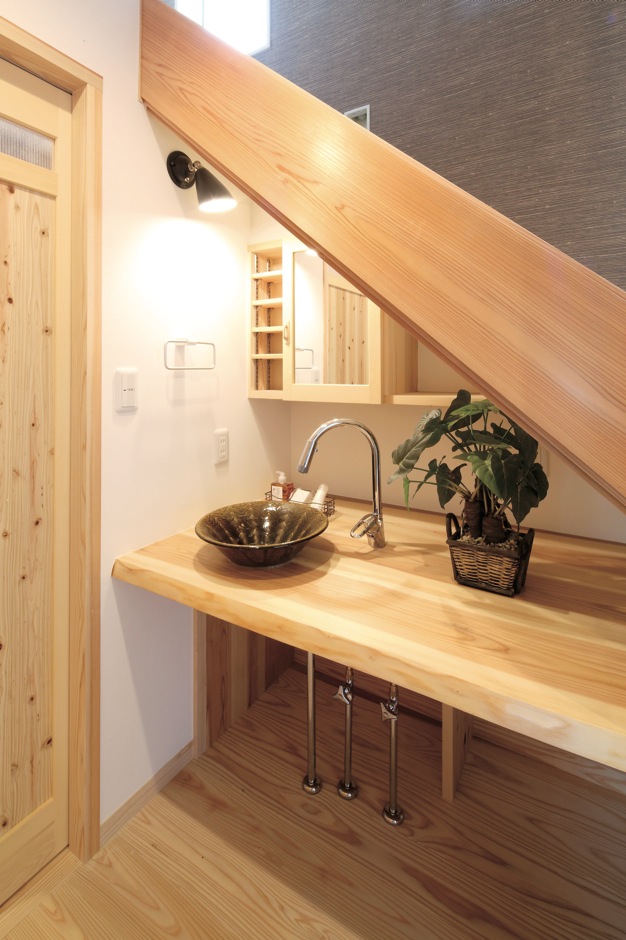 アクトホーム【自然素材、省エネ、間取り】階段下を利用した洗面スペース。大井川スギのカウンターに、手水鉢には遠州七窯の1つとして知られる地元の「志戸呂焼」が使われた