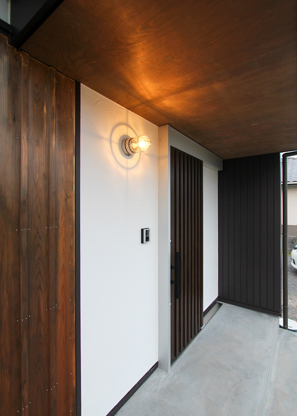 アクトホーム【子育て、自然素材、省エネ】室内よりも暗い色味の素材を選定し、落ち着いた雰囲気の玄関。厳選した照明もお洒落