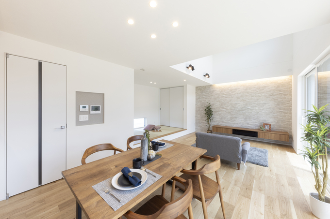 明るいリビングダイニングキッチン。広々とした空間に、木製のダイニングセットとシンプルなインテリアが調和している。