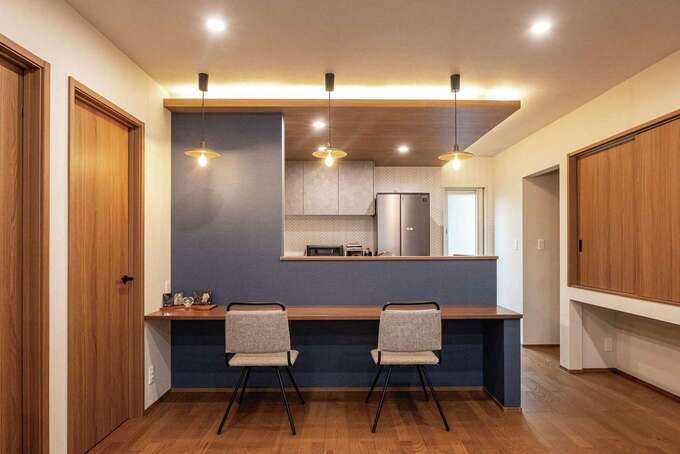 カフェスタイルのオープンキッチン。水回りへの動線もスムーズで家事時間を短縮できる。キッチンの下がり天井と間接照明がおしゃれ