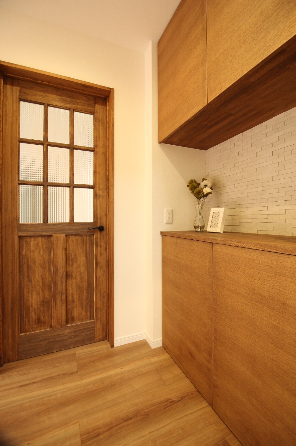 小野田産業～designers house project～｜親世帯と共有の玄関はゆったりとした設計でこれからの暮らしを考えた間取り。
温かみのある木目調のフローリングとドアが調和し、落ち着いた雰囲気を醸し出している。