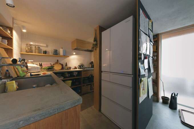 モルタル土間のキッチンは奥さまのお気に入り。冷蔵庫を中心に回遊できる空間は、全体がパントリーのような収納力。オープン棚で必要なものにさっと手が届く