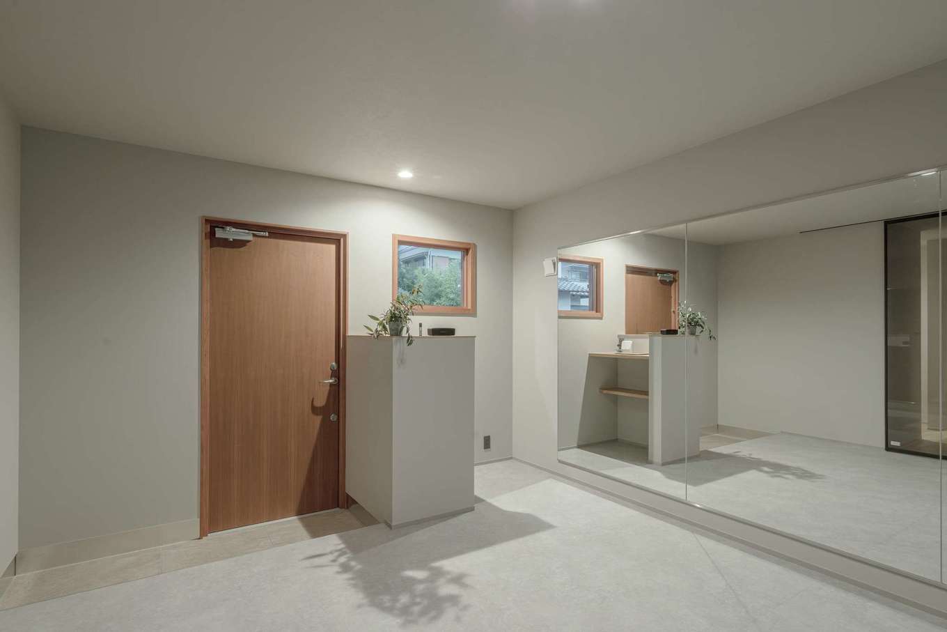住家 JYUKA【デザイン住宅、趣味、間取り】奥さまはフィットネス・バレエ・ヨガの要素を組み合わせたバレトンの講師。スタジオには適度な踏み心地の床材と大きな鏡が採用され、トレーニンググッズを収納するスペースや受付台なども用意された。窓によって切り取られた借景のグリーンがリラックスを運ぶ
