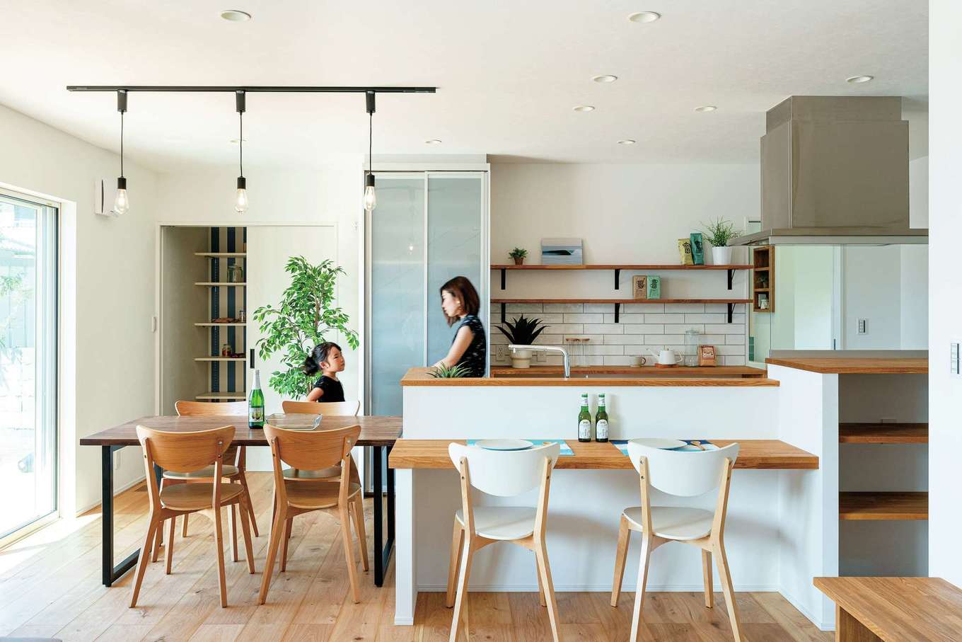KUREKEN HAUS（榑林建設）【デザイン住宅、省エネ、間取り】「既製品は好きじゃなくて」という夫妻は、カウンターや棚を造作仕立てに。左奥はパントリーで、右奥は水回り。横並びのダイニングテーブルとともに、家事効率アップに貢献