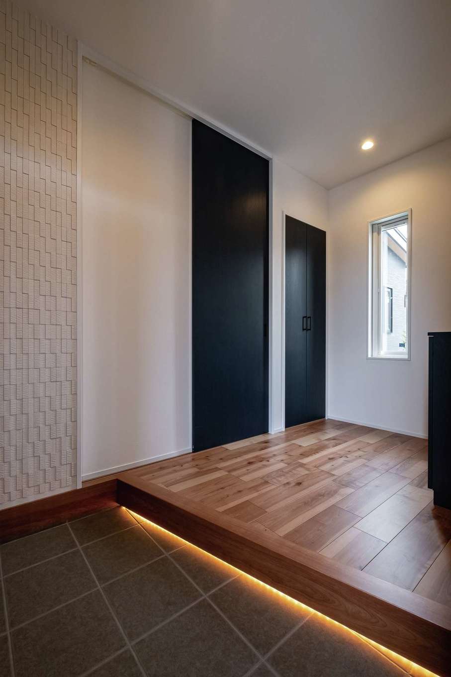 臼幸産業【デザイン住宅、省エネ、間取り】玄関にも間接照明を。帰宅する家族を優しく出迎えてくれる。壁には快適な空間づくりに一役買うエコカラットを用いた