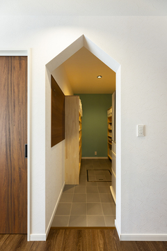 三角屋根の垂れ壁で遊び心を取り入れたパントリー。出しやすくしまいやすい収納棚を造作するとともに、冷蔵庫もこの中に隠してLDKに生活感を出さないようにした