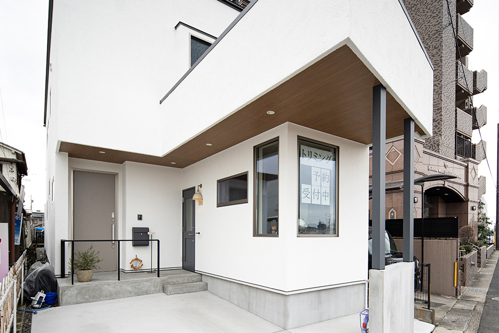 CSホームズ｜夢を叶えた住宅兼ペットサロン店舗。凹凸のあるモダンなデザインの外観。白い壁面とウッドの組み合わせが洗練された印象を与えている。