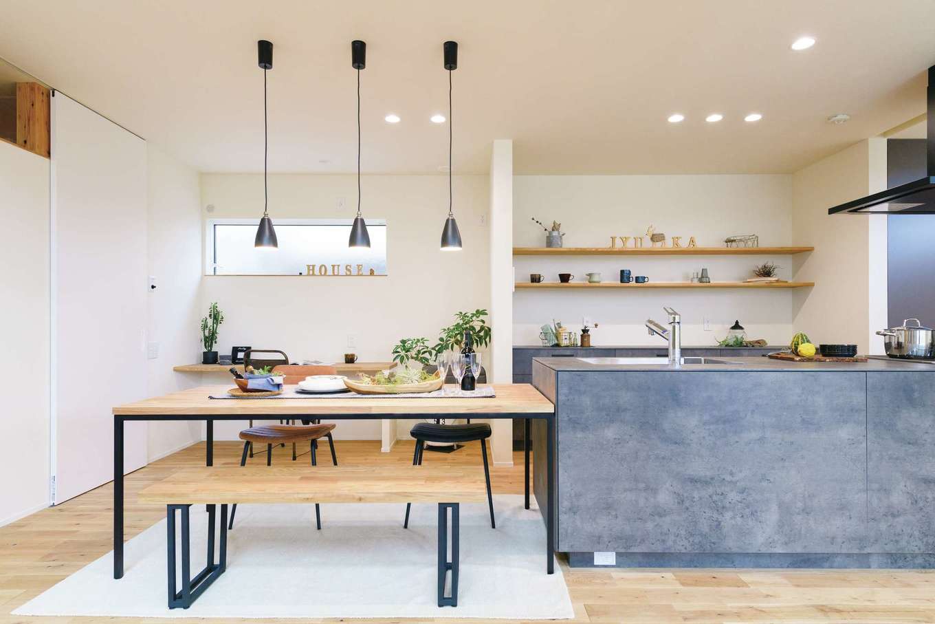 住家 JYUKA【デザイン住宅、間取り、建築家】カフェのようなキッチン。見せて収納する壁のシェルフがおしゃれ。ダイニングスペースにもカウンターデスクを造作。子どものスタディコーナーやパソコンスペースに