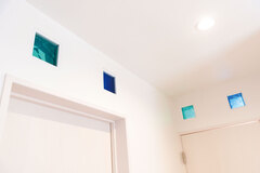 各部屋の入口や２階廊下には、ガラスブロックがちりばめられている。カラフルな色彩がシンプルな空間のアクセントに