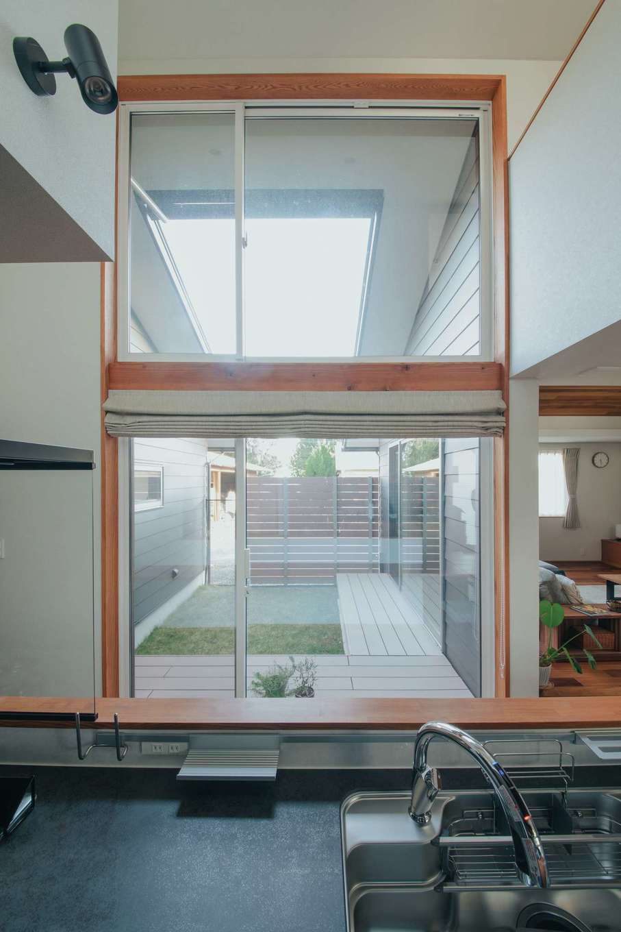 神谷綜合建設 カミヤの家【デザイン住宅、和風、間取り】２層吹抜けの大窓から、たっぷりの光が降り注ぐ。毎日の家事がグッと快適に。「キッチンに立つと、中庭の向こうに空が広がって、とっても気持ちがいいんです」と奥さま。朝からたっぷりの光が差し込み、晴れの日なら電気をつける必要もなし。仕事に、家事に忙しい奥さまを癒やしてくれる特等席。