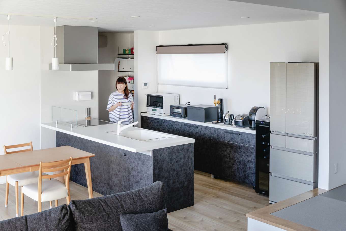 吉川住建【デザイン住宅、夫婦で暮らす、平屋】グレイッシュな床の色と質感に合わせてセレクトしたオープンキッチン。料理しながらテレビや庭の景色が見える