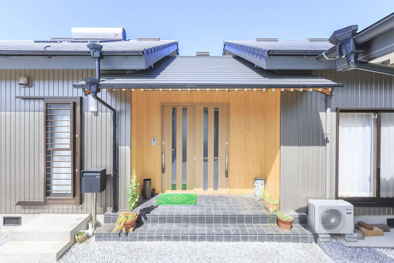 まちの大工さん 鈴木工務店【夫婦で暮らす、間取り、平屋】玄関は平屋の中央に配置。深く出した庇やポーチ部分の板張りの外壁が、数寄屋風の情緒を感じさせる