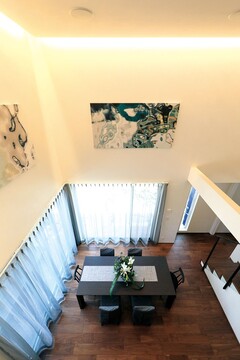 吹き抜けが特徴的なダイニングエリア。大きな窓から光が差し込み、開放感あふれる空間になっている。上品なアートが壁を飾っています。