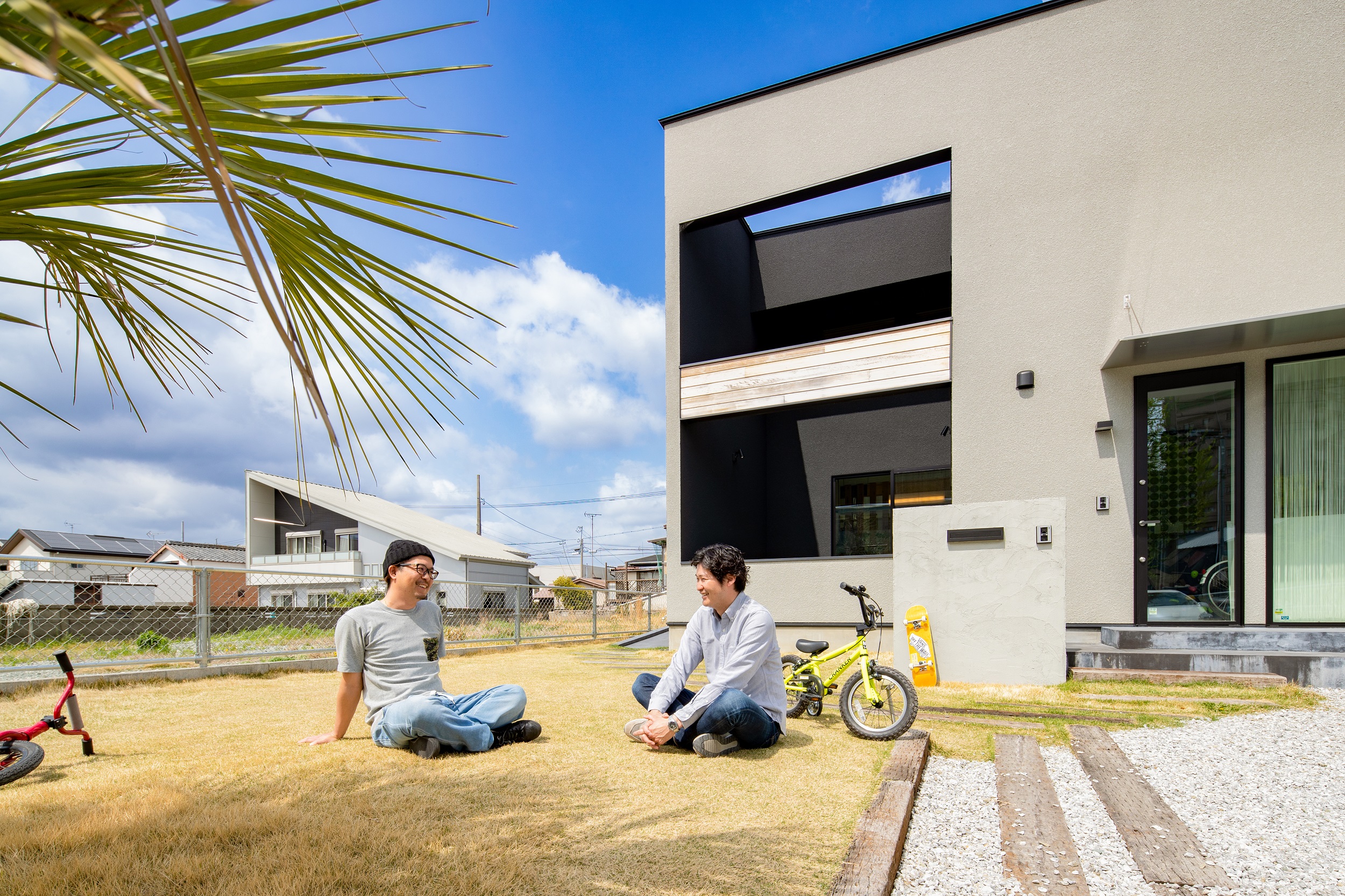 S.CONNECT（エスコネクト）【デザイン住宅、子育て、建築家】芝生の庭で談笑するご主人と『エスコネクト』の杉浦社長。理想通りの家が完成し、互いに満足そうな笑顔をみせる。「社長は、家を建てる前よりも建った後の方がひんぱんに連絡をくれるようになったよね（笑）。家によく遊びに来てくれるのも嬉しいです」とご主人