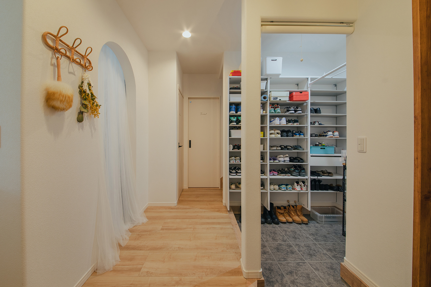 子育て安心住宅 Design Craft Office【デザイン住宅、子育て、間取り】シューズクロークのある家族用玄関を上った正面には、アーチ型の出入り口。その先にはファミリークローゼットになっているので、すぐに着替えができる