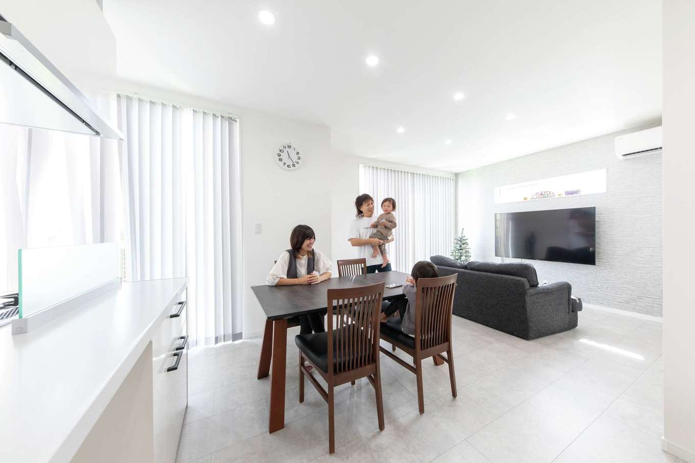 アフターホーム【1000万円台、デザイン住宅、間取り】ホワイトを基調に、床材、クロス、ブラインドなどの素材で変化をつけたモダンなLDK。天井高は2.5メートルと通常より高めにしていて、実際の面積よりも部屋が広く感じられる。断熱性能が高いためエアコンの効きがよく、新居での初めての夏は快適に過ごせたそう